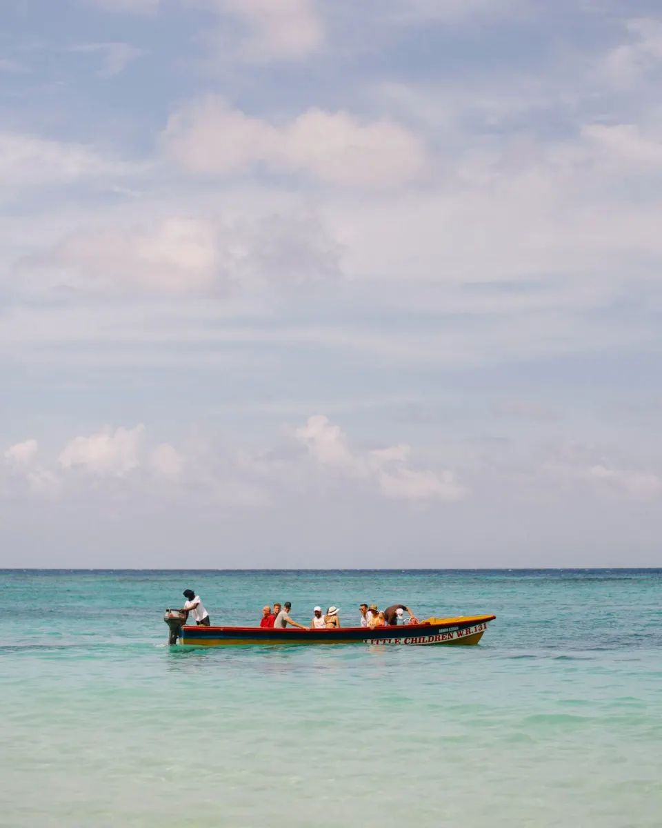 Guests ride a small boat across the turquoise sea by Jamaica Inn.