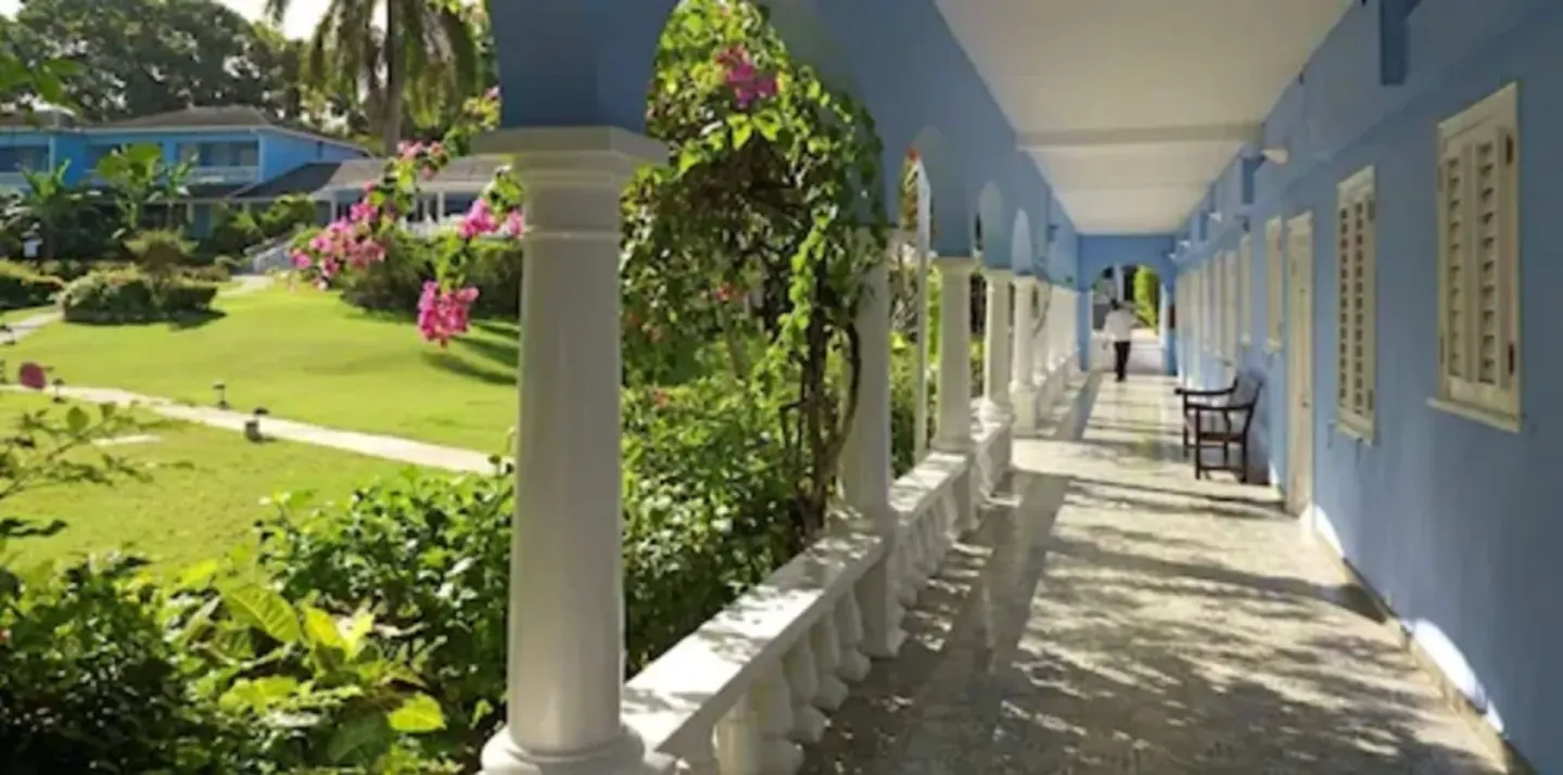 Blue guest building corridor with white arches and garden views at Jamaica Inn.