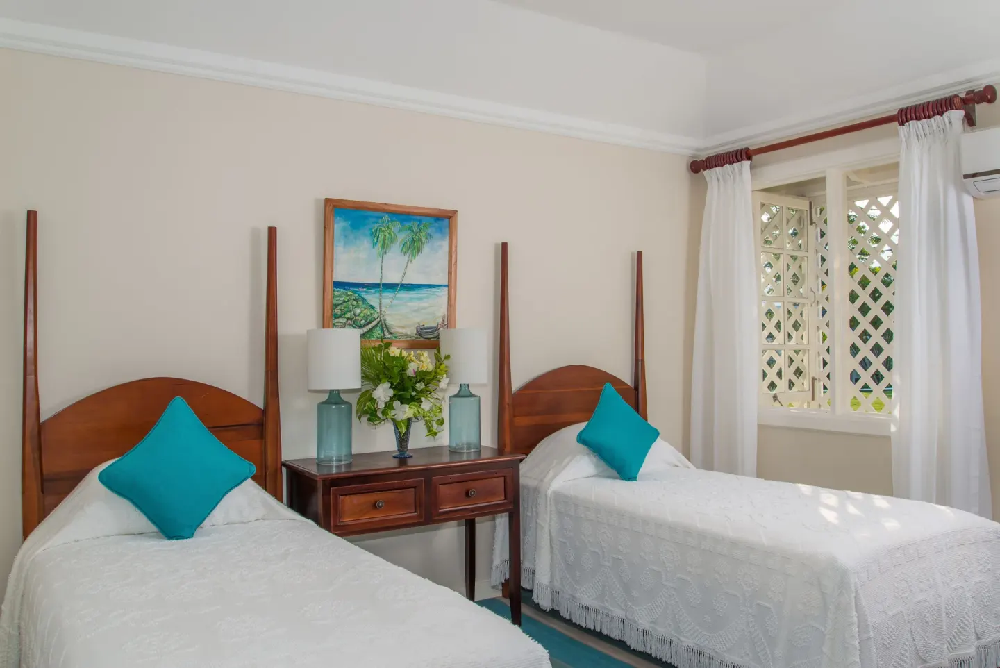 Twin beds with white covers and turquoise pillows in a guest room at Jamaica Inn.