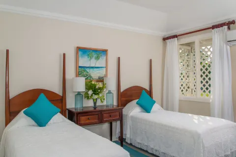 Twin beds with white covers and turquoise pillows in a guest room at Jamaica Inn.