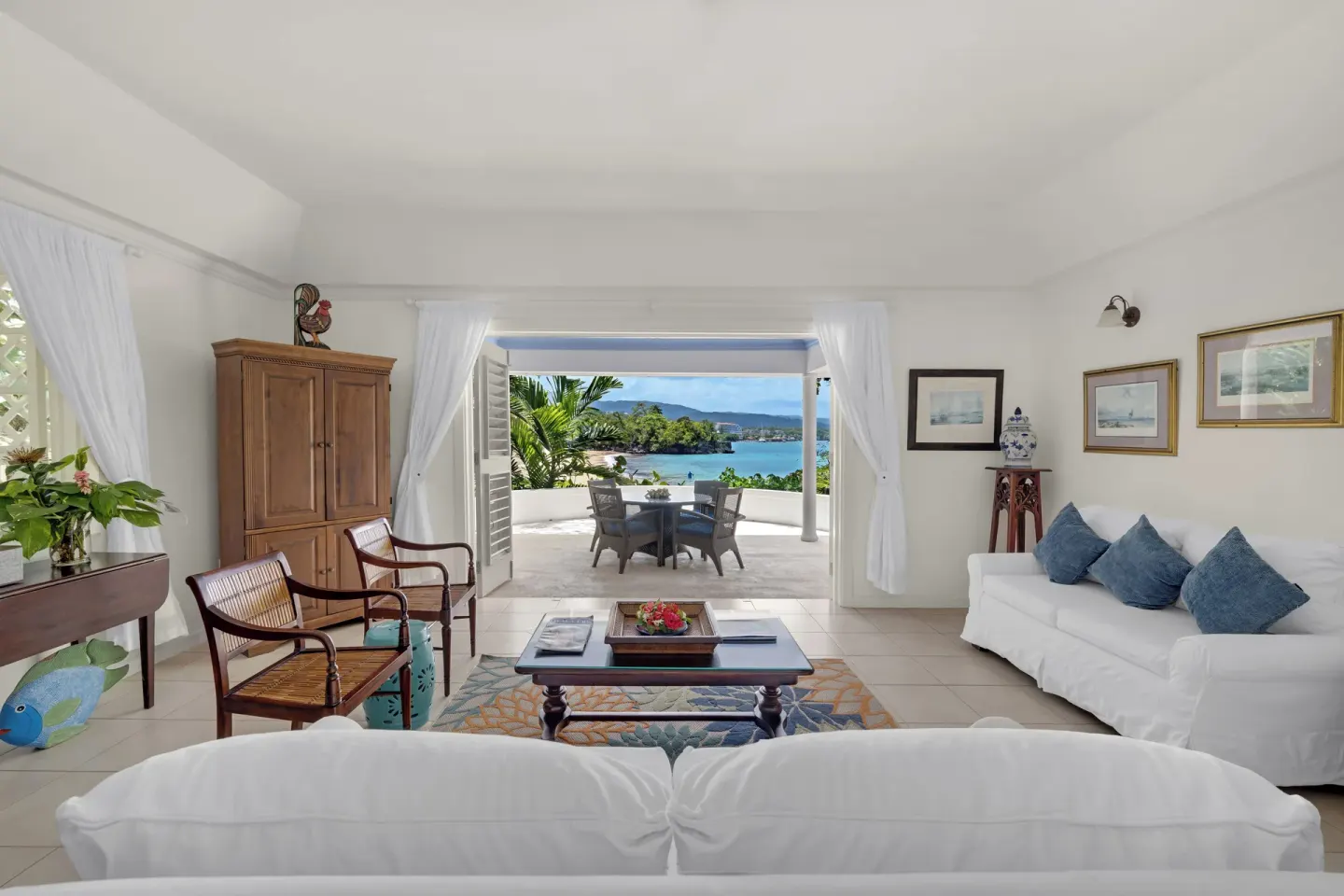 Oceanfront living room with white sofas and terrace view at Jamaica Inn.