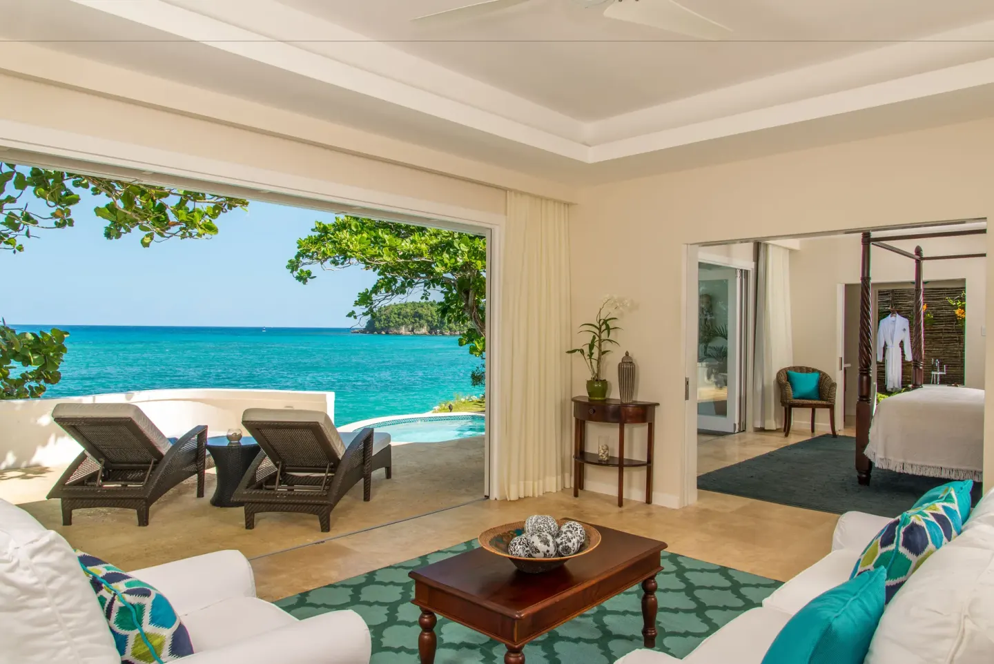 Oceanfront suite living area and bedroom with terrace loungers at Jamaica Inn.