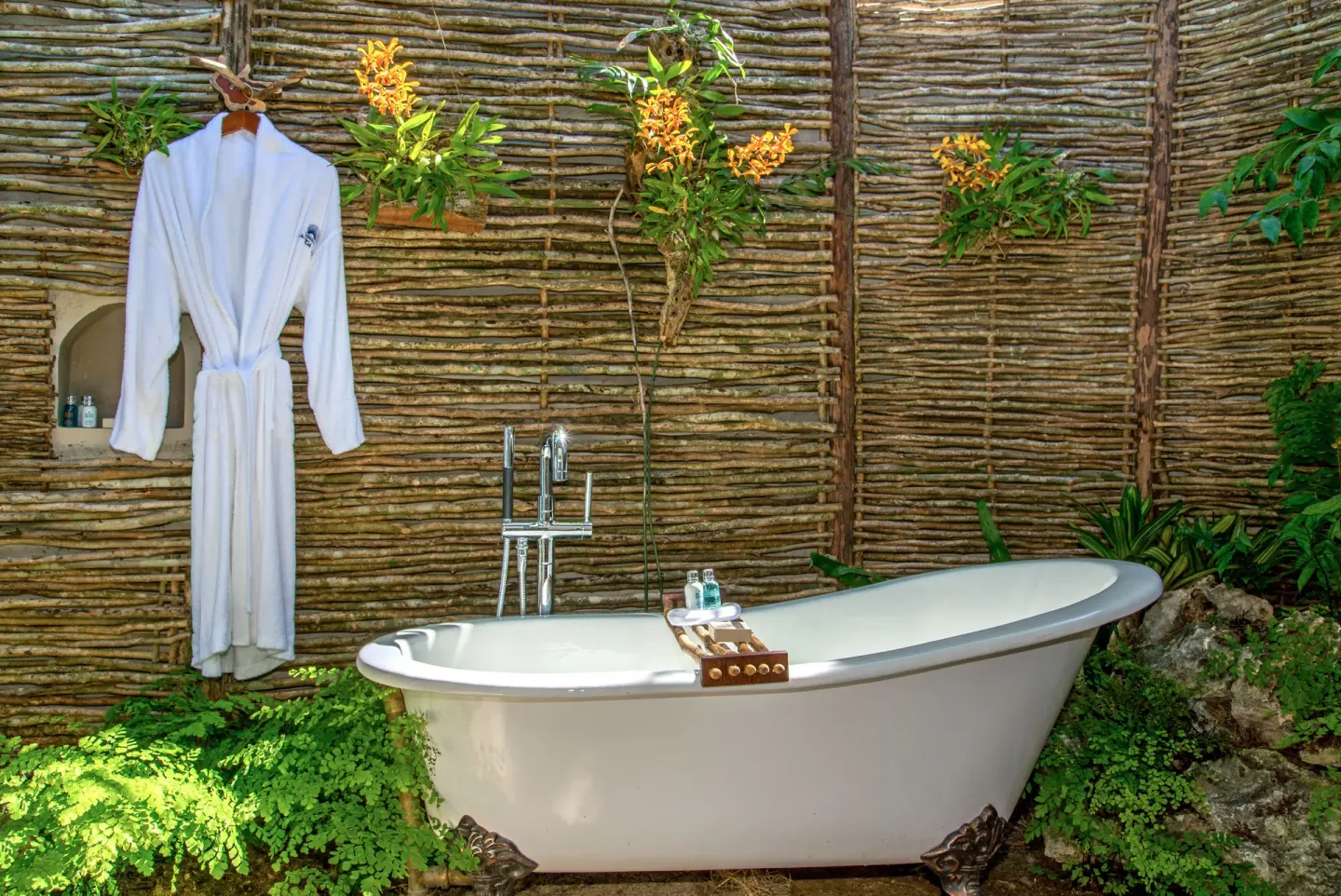 Outdoor soaking tub with a white robe and woven privacy wall at Jamaica Inn.