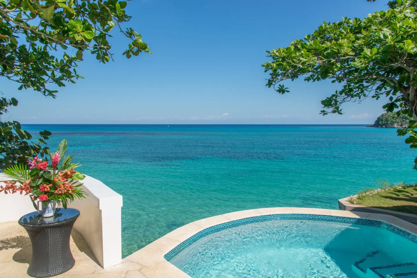 Small pool terrace overlooking turquoise sea beneath trees at Jamaica Inn.