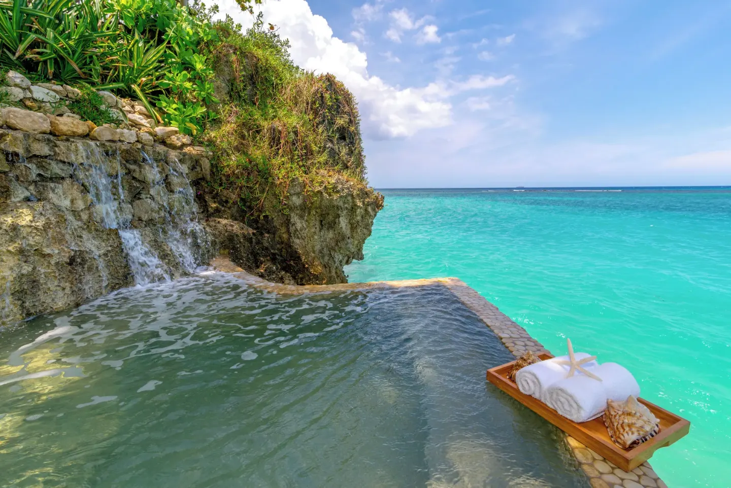 Seaside pool with waterfall and turquoise water at Jamaica Inn.