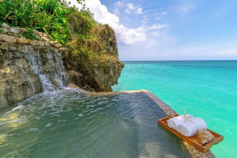 Seaside pool with waterfall and turquoise water at Jamaica Inn.