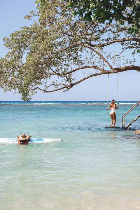 A guest uses a tree swing over the shallow sea at Jamaica Inn.