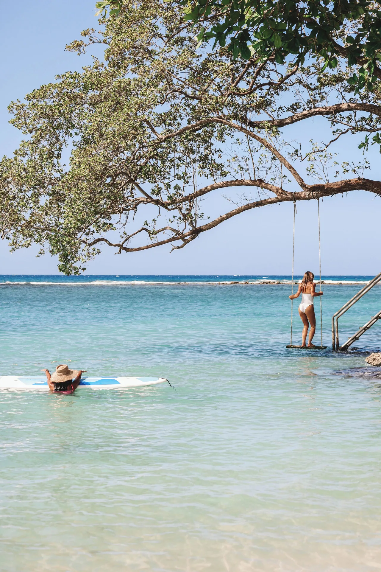 A guest uses a tree swing over the shallow sea at Jamaica Inn.