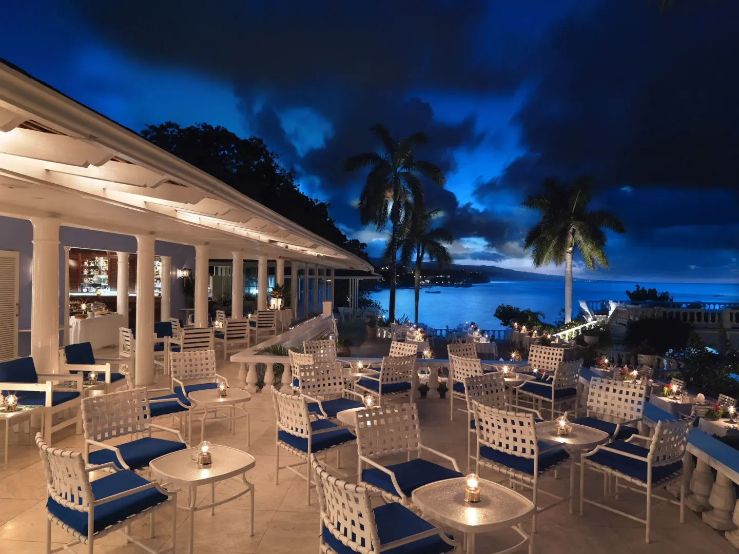 Candlelit terrace seating overlooks the sea at night at Jamaica Inn.