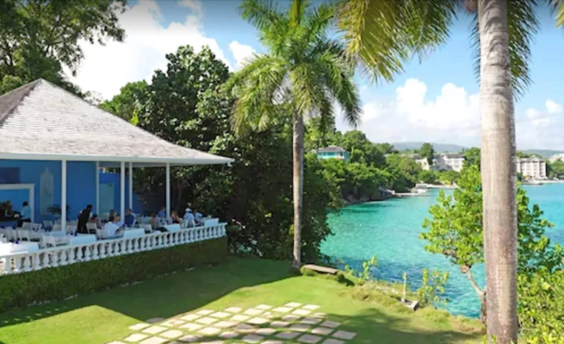 Open-air restaurant terrace beside turquoise water and palms at Jamaica Inn.