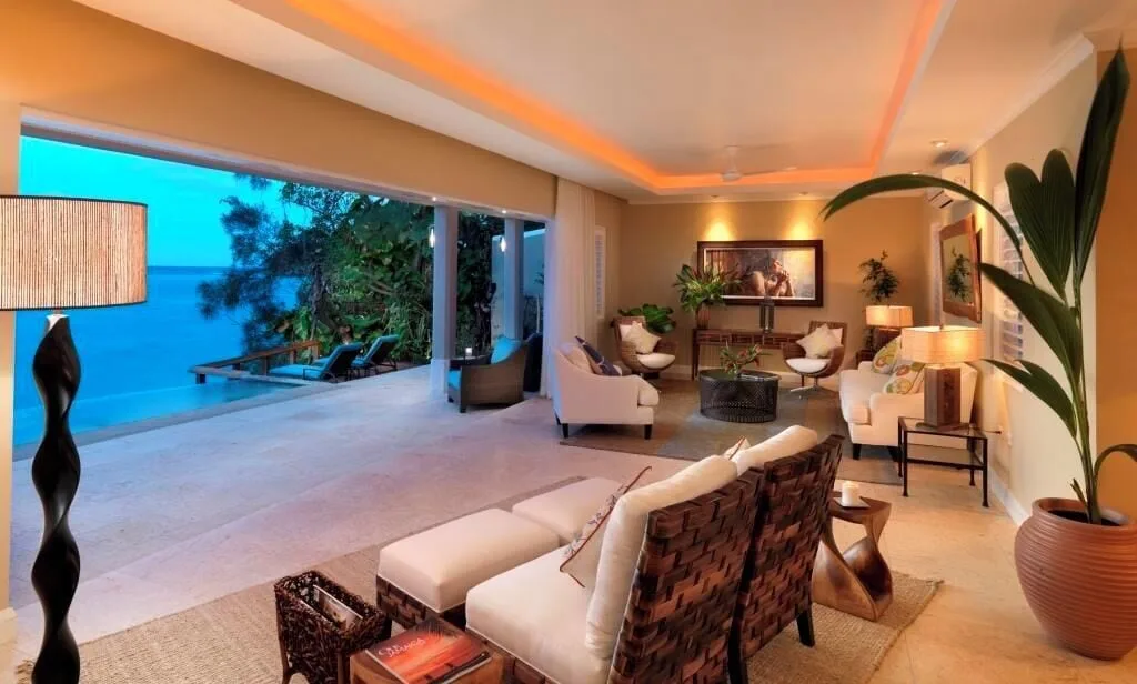 Cottage Seven lounge with sofas, lamps, terrace, and ocean view at Jamaica Inn.