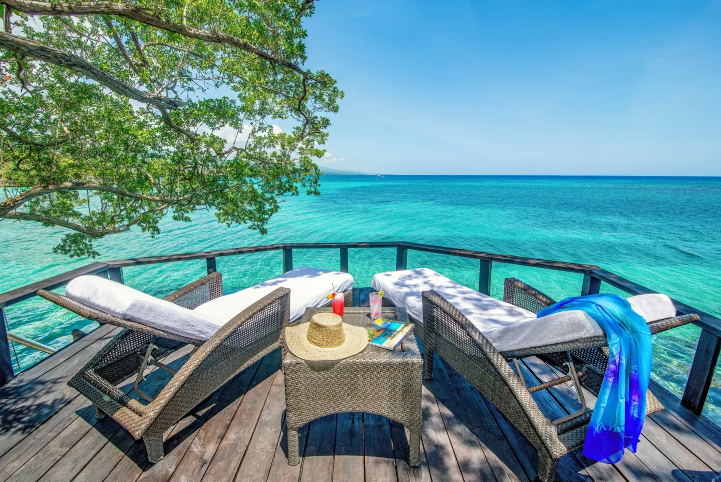 Cottage Three deck at Jamaica Inn with lounge chairs over turquoise water.