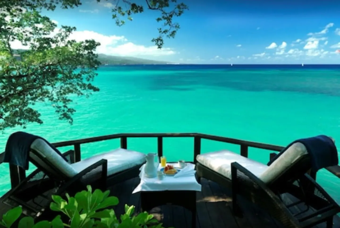 Cottage Three deck at Jamaica Inn with two loungers facing turquoise sea and distant hills.