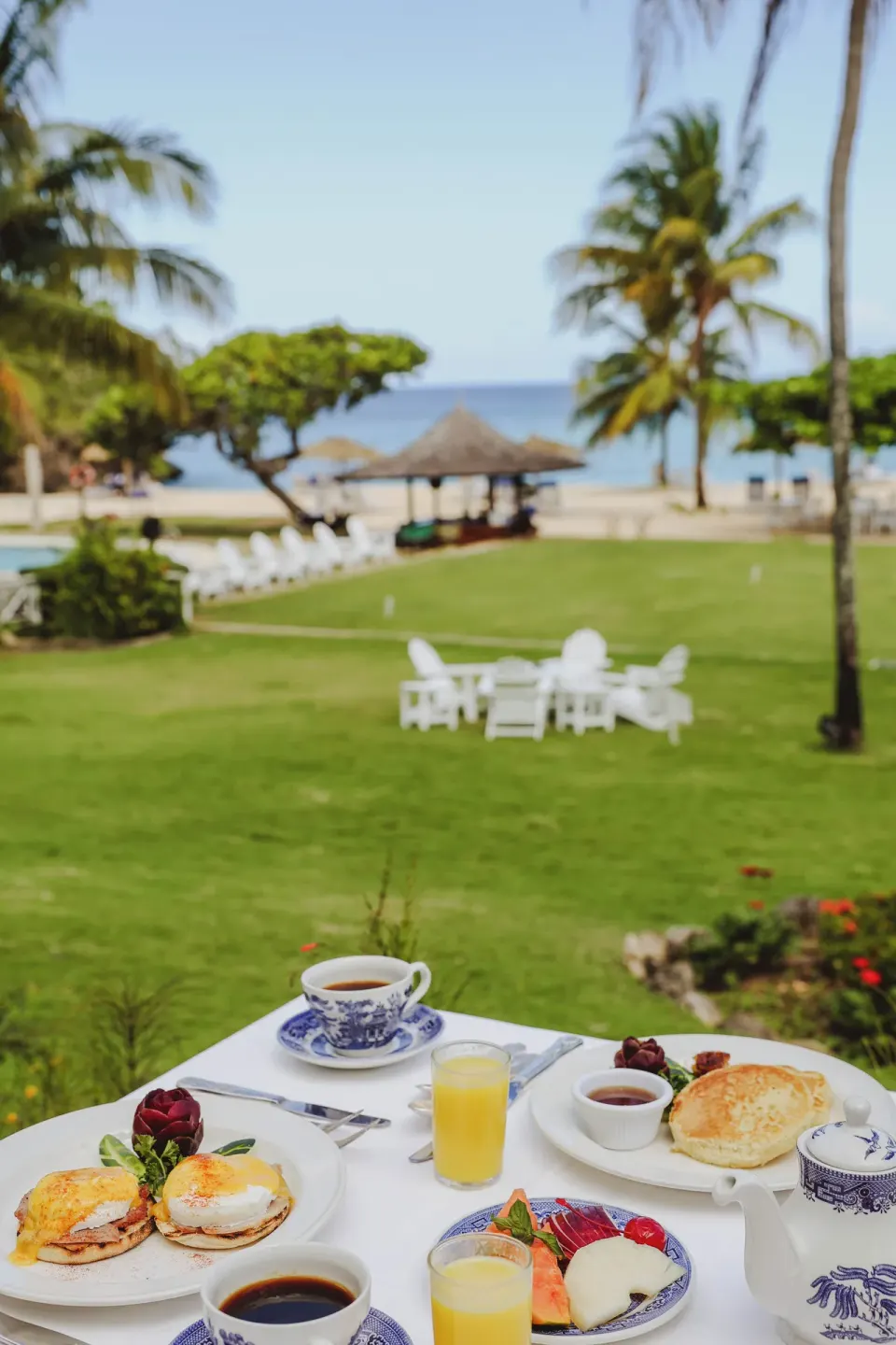 Deluxe Suite verandah breakfast with lawn, palms, and sea view at Jamaica Inn.