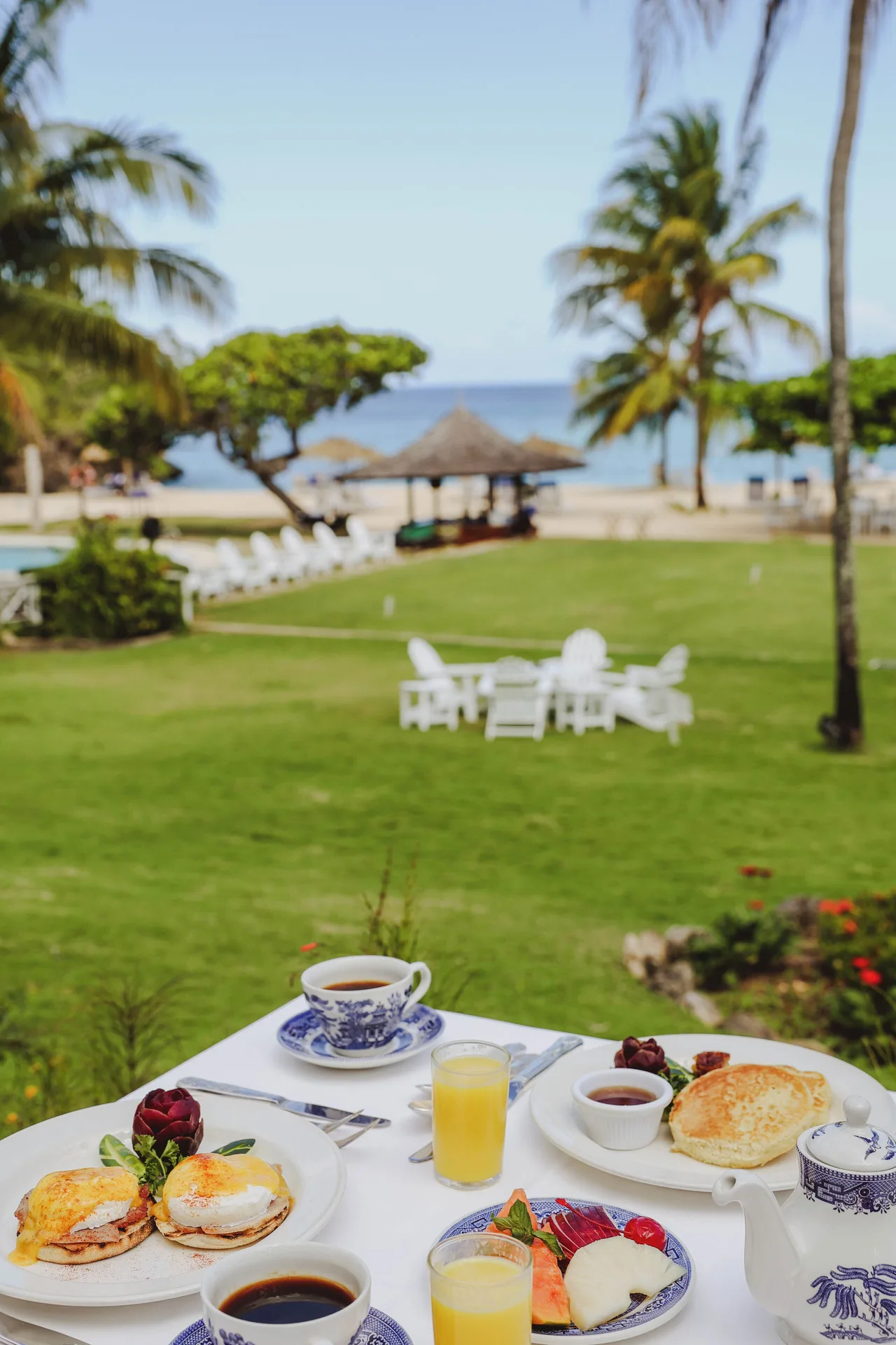 Deluxe Suite verandah breakfast with lawn, palms, and sea view at Jamaica Inn.