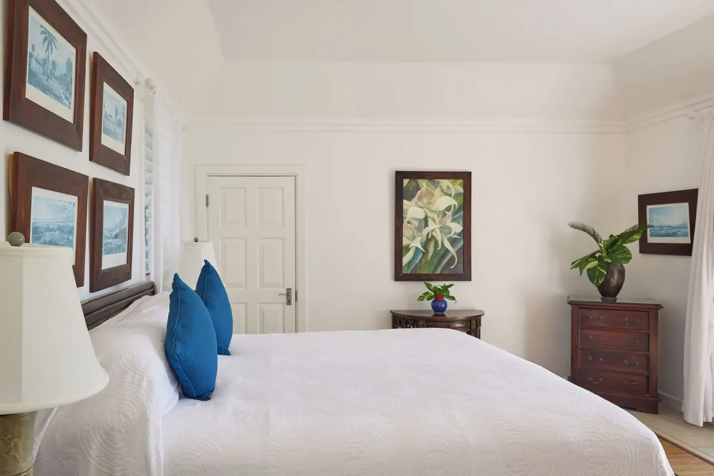 Deluxe Suite bedroom with white bed, blue pillows, and framed artwork at Jamaica Inn.