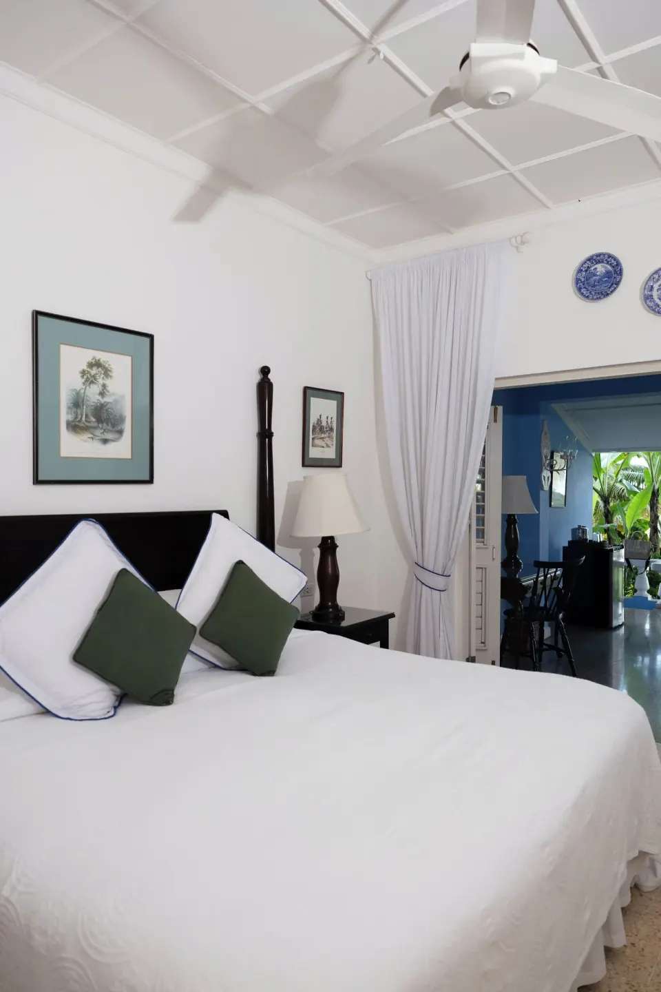 Deluxe Suite king bed with high ceiling and doorway to sitting area at Jamaica Inn.