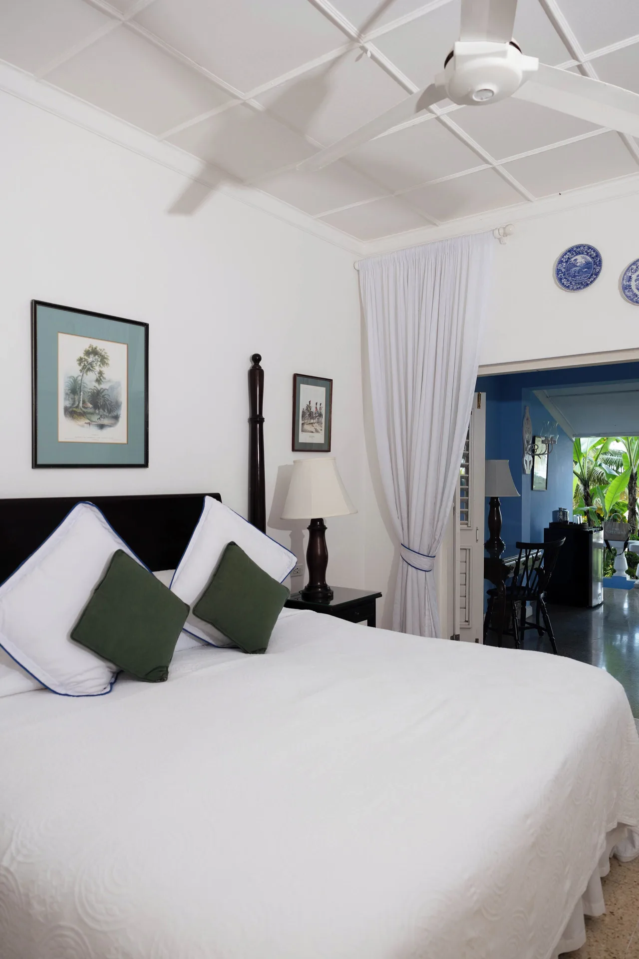 Deluxe Suite king bed with high ceiling and doorway to sitting area at Jamaica Inn.