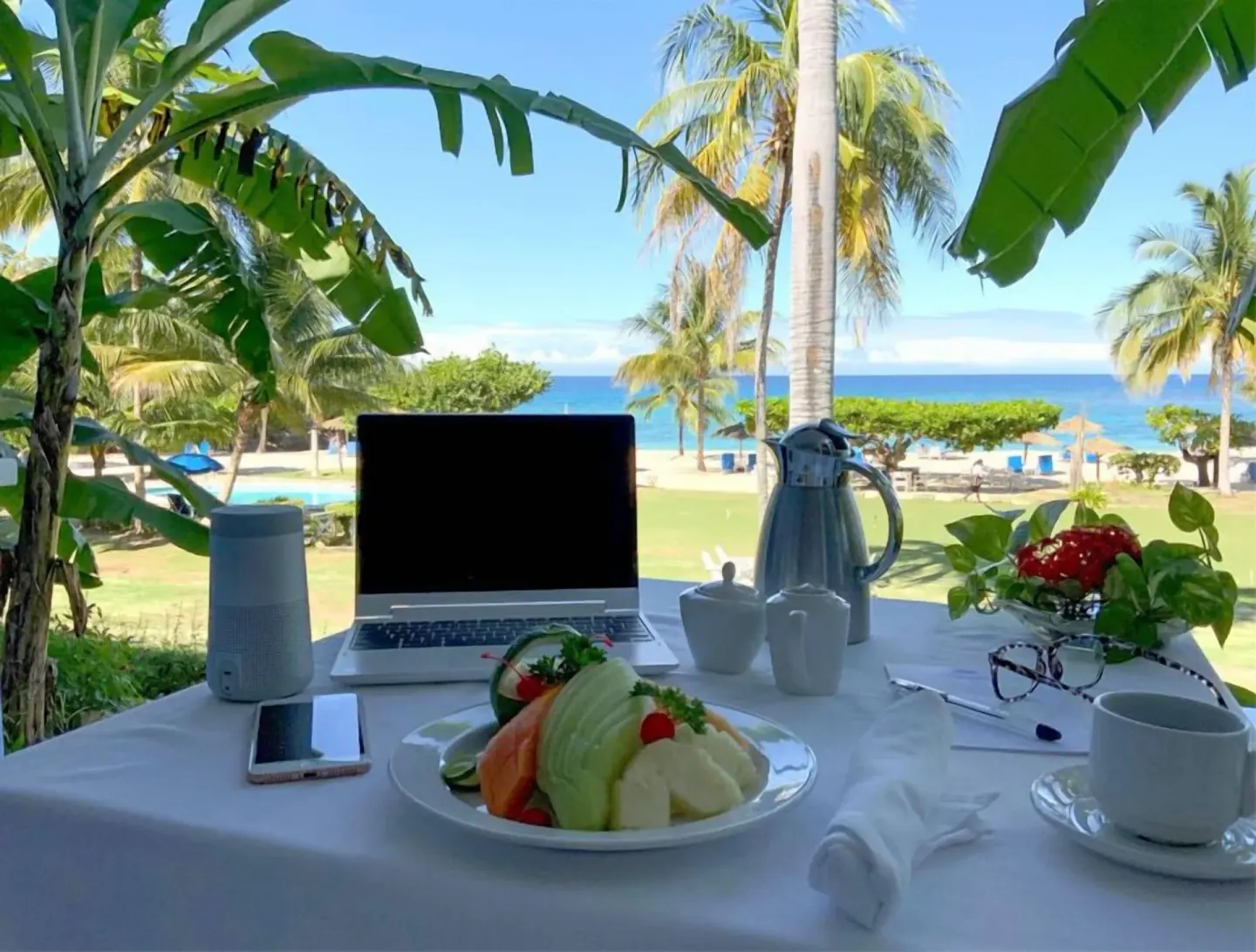 Deluxe Suite verandah table with laptop, fruit, coffee, and ocean view at Jamaica Inn.