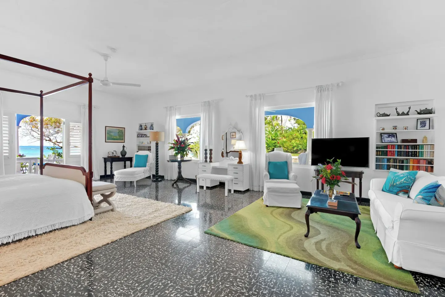 Suite 21 at Jamaica Inn with a four-poster bed, lounge seating, TV, and arched windows.