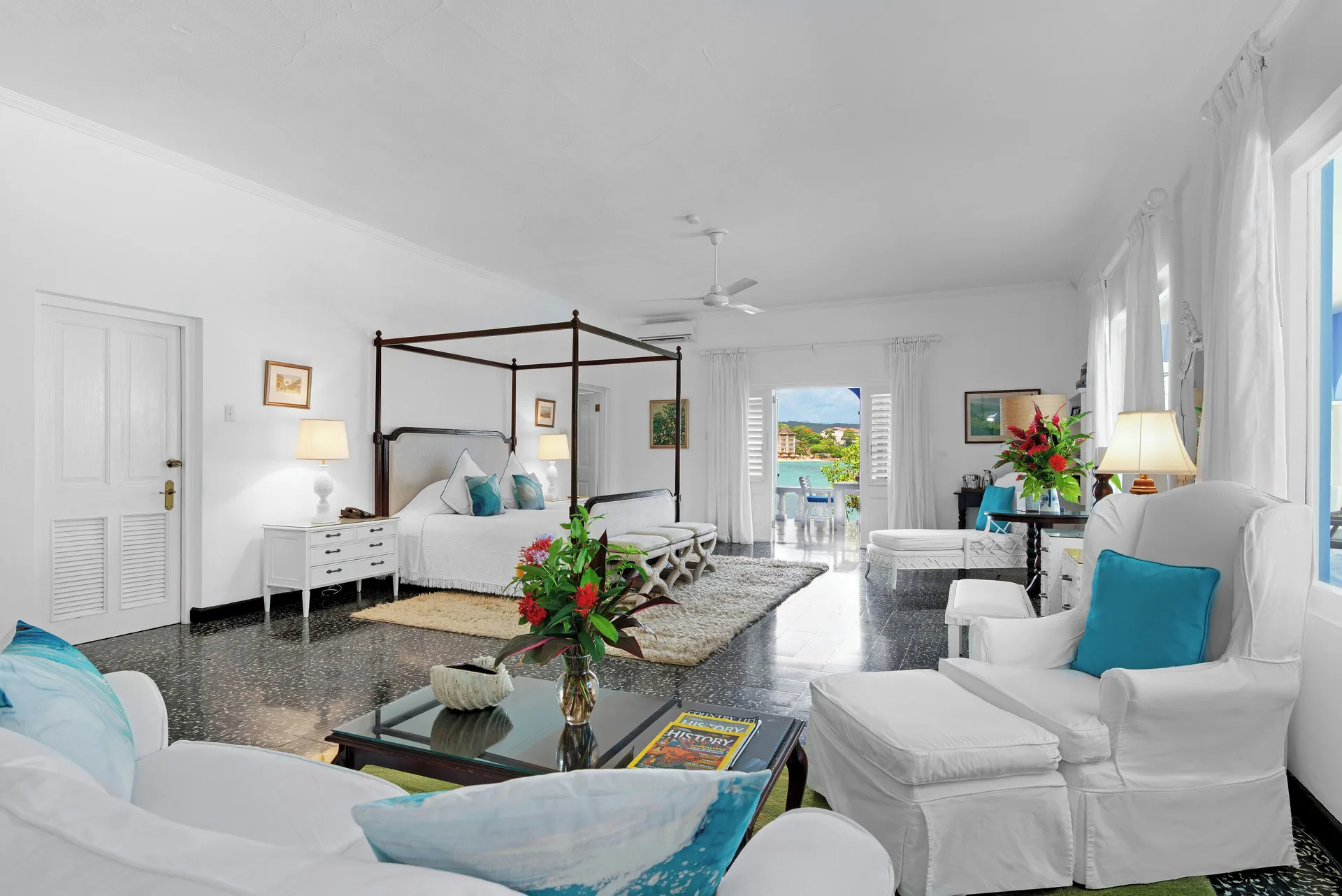 Suite 21 at Jamaica Inn with a four-poster bed, sitting area, and open balcony doors to the sea.