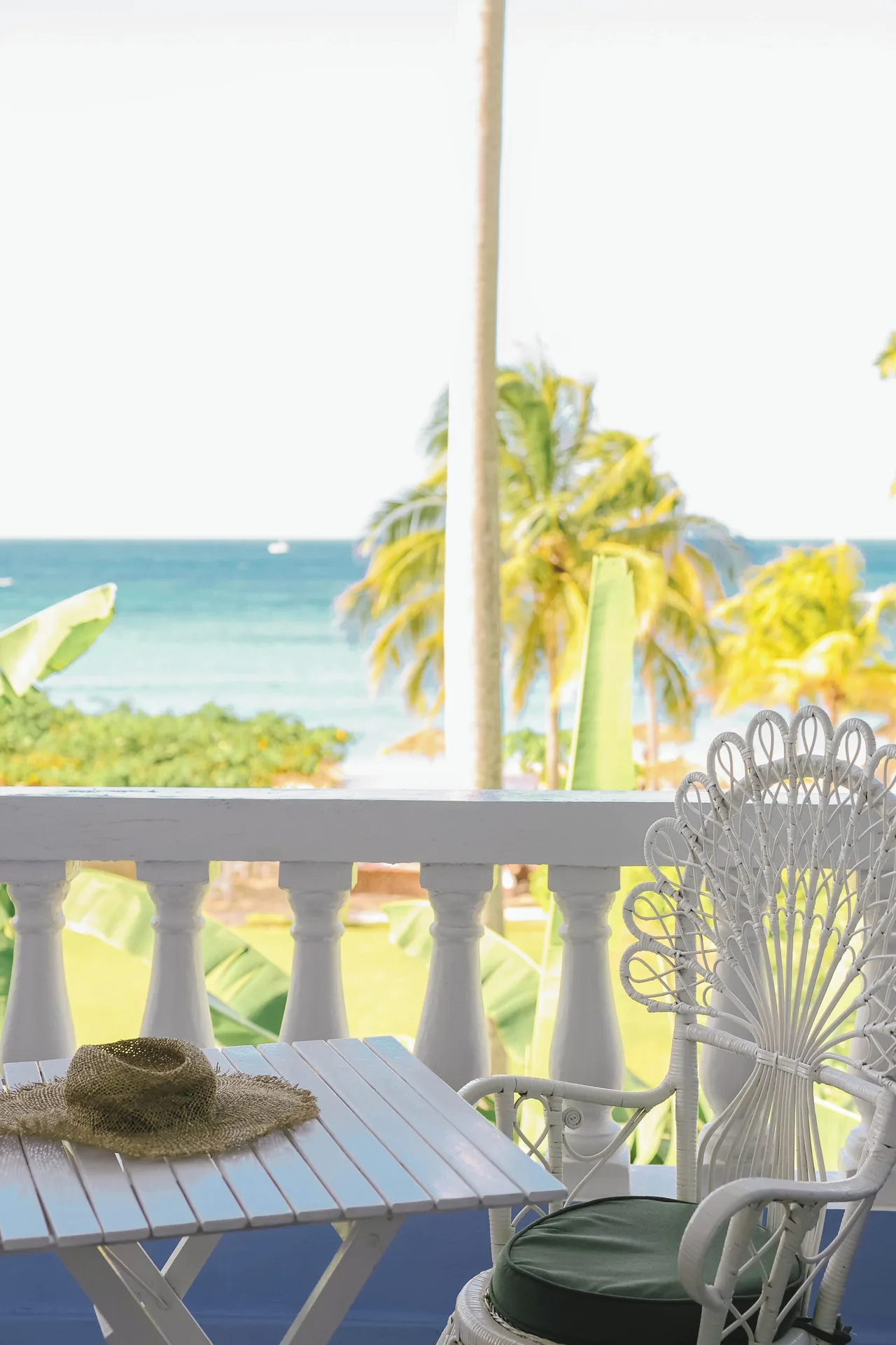 Balcony seating with a white wicker chair and ocean view at Jamaica Inn.