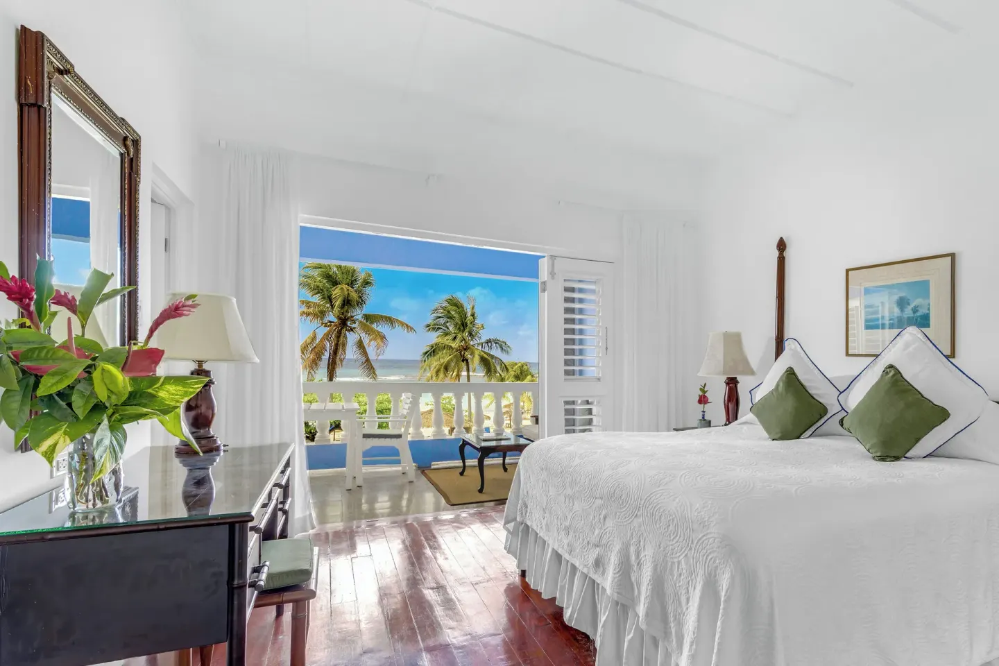 Balcony suite bedroom with a white bed and ocean view at Jamaica Inn.