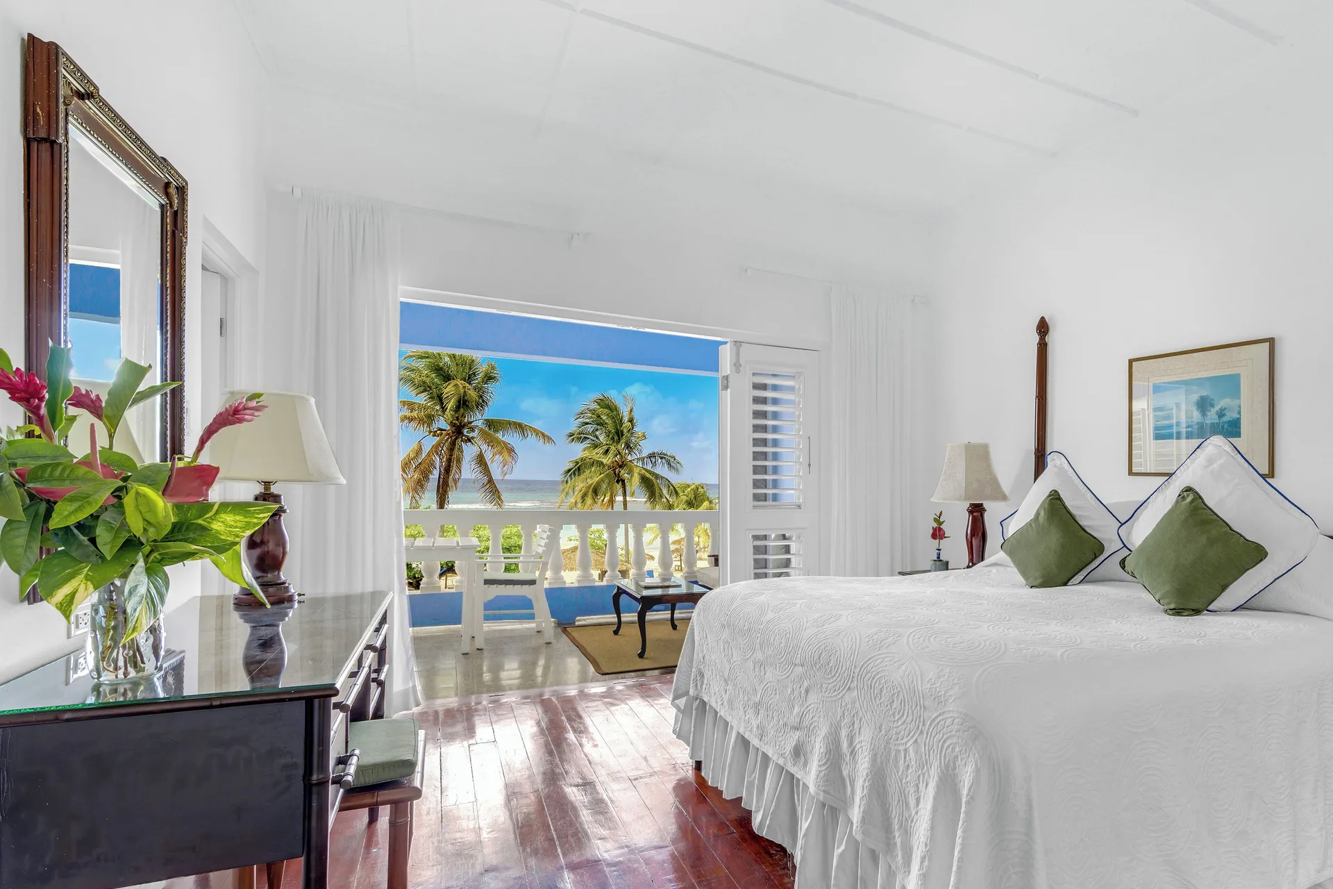 Balcony suite bedroom with a white bed and ocean view at Jamaica Inn.