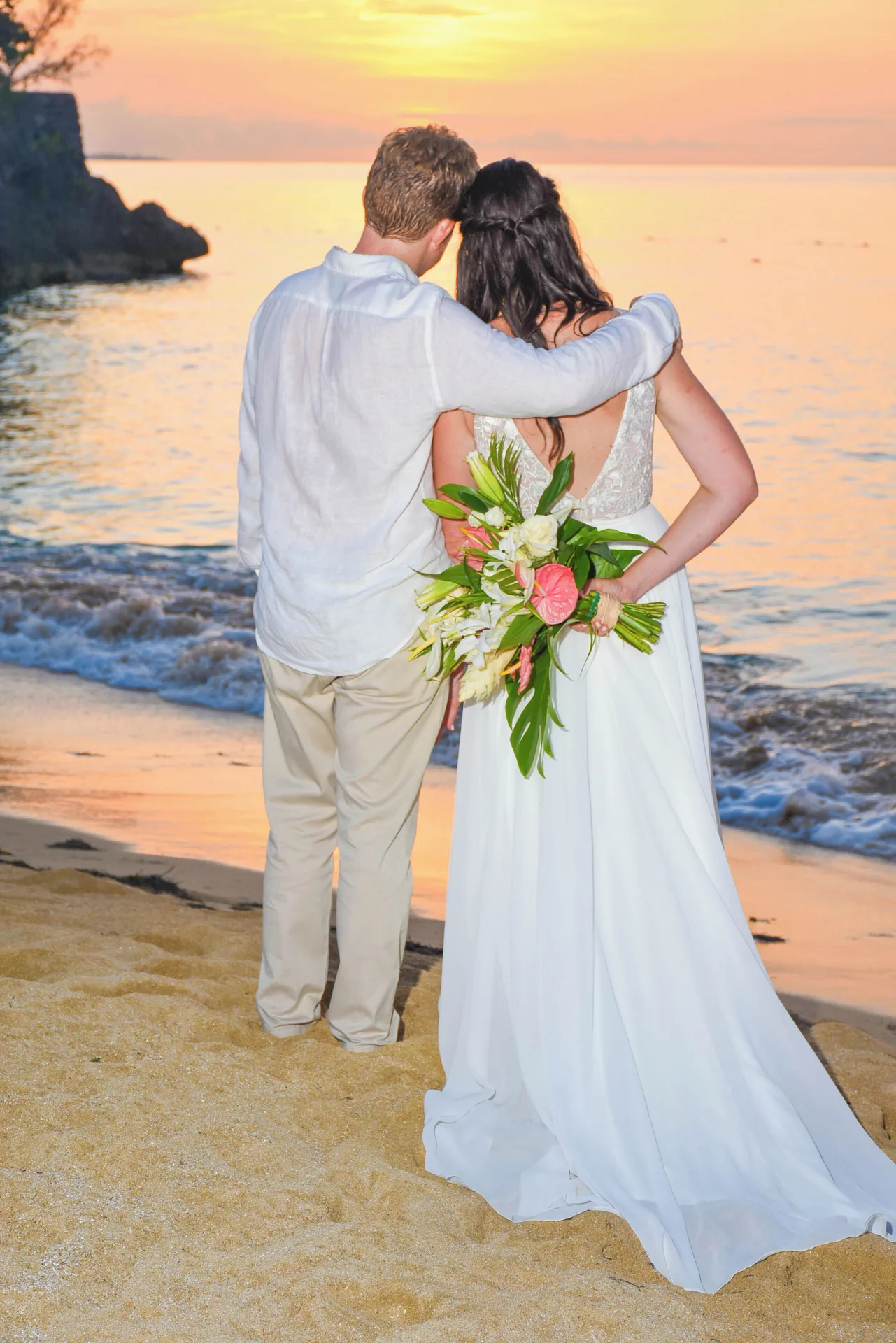 Bride and groom standing on the beach at sunset at Jamaica Inn.