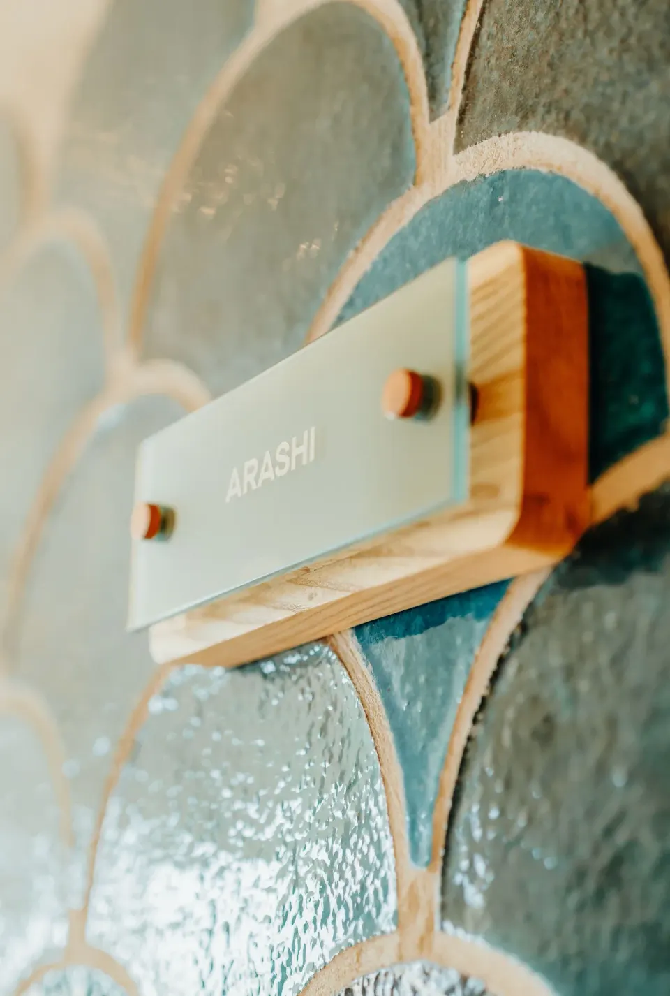 Frosted Arashi sign mounted on blue scalloped tile at JOIA Aruba.