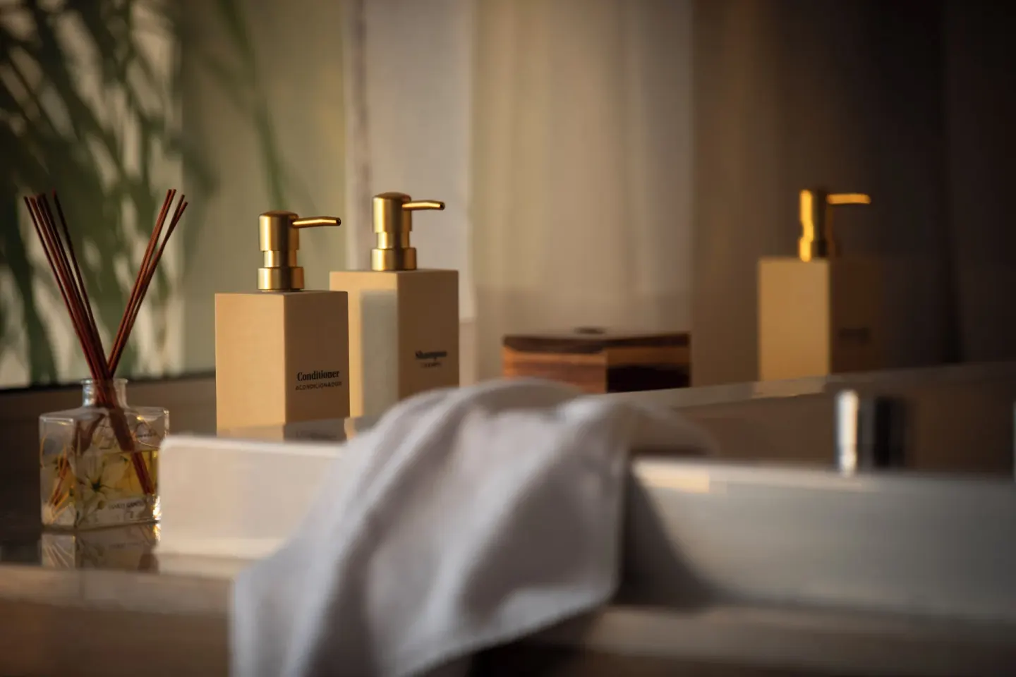 Bath amenities, a diffuser, and a towel sit beside a sink at JOIA Aruba.