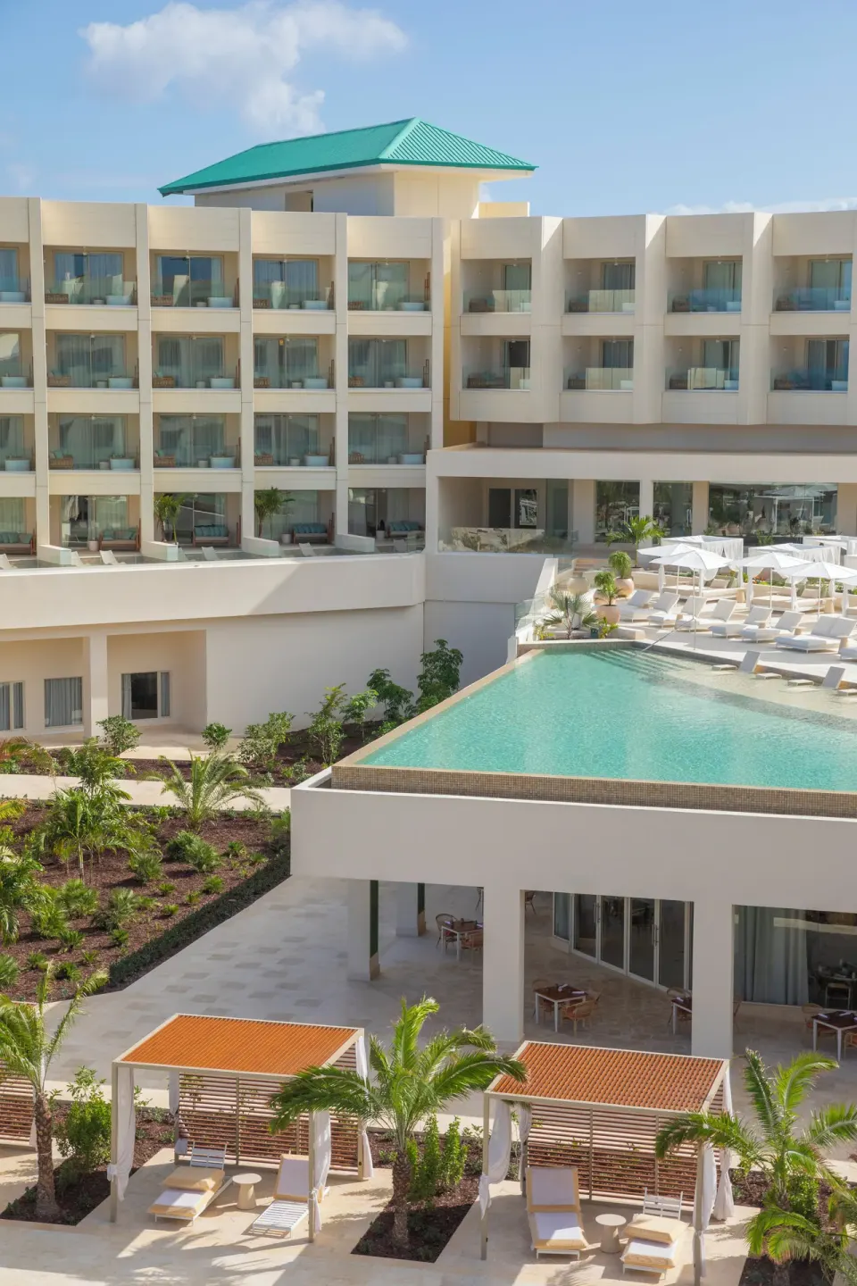 Elevated pool terrace and resort balconies with cabanas below at JOIA Aruba.