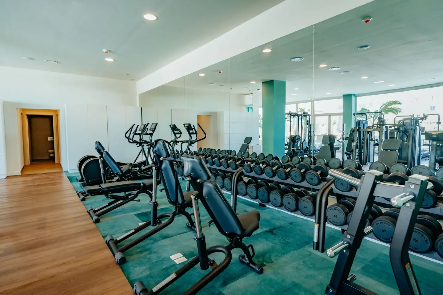 Fitness center with weights, cardio machines and mirrored wall at JOIA Aruba.