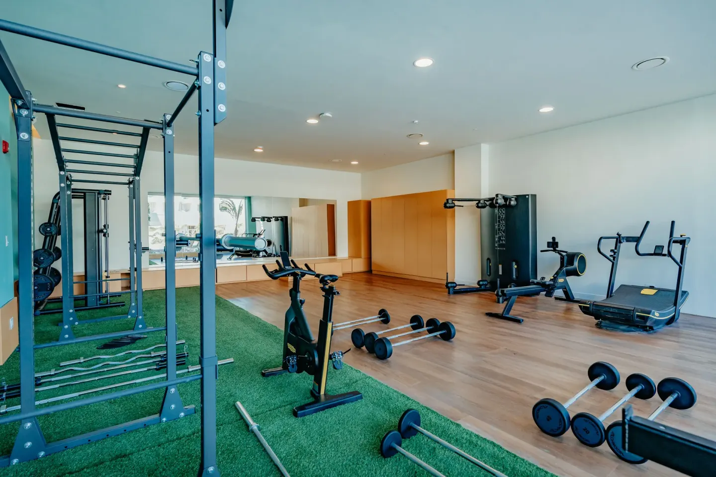 Open fitness area with turf, squat rack, bike and free weights at JOIA Aruba.