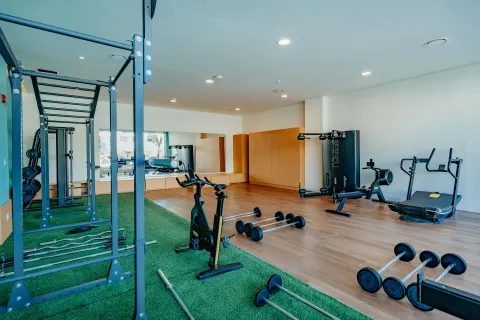 Open fitness area with turf, squat rack, bike and free weights at JOIA Aruba.