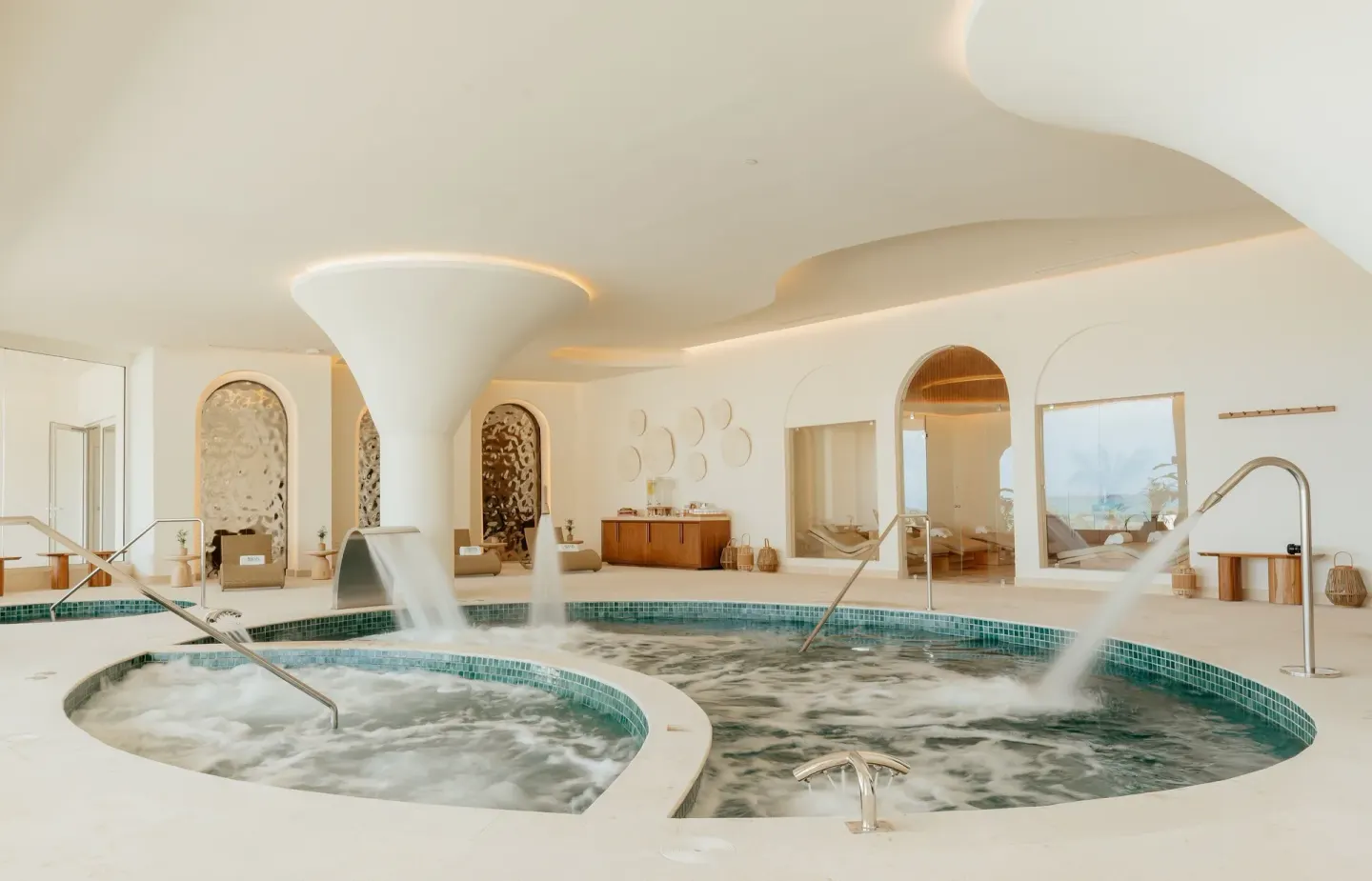 Indoor spa pools with bubbling water jets and curved architecture at JOIA Aruba.