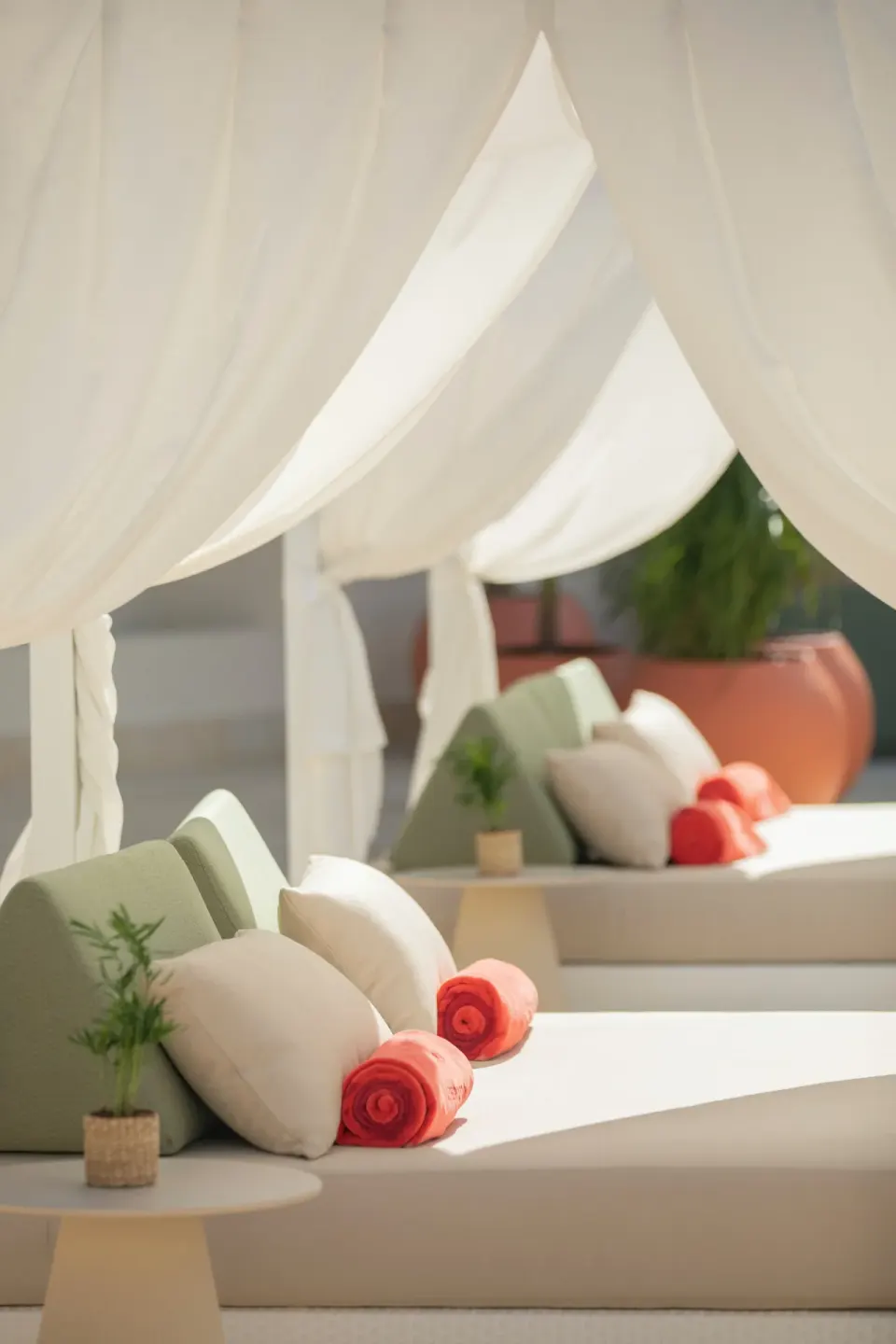 Poolside cabanas with white drapes, pillows, and rolled towels at JOIA Aruba.
