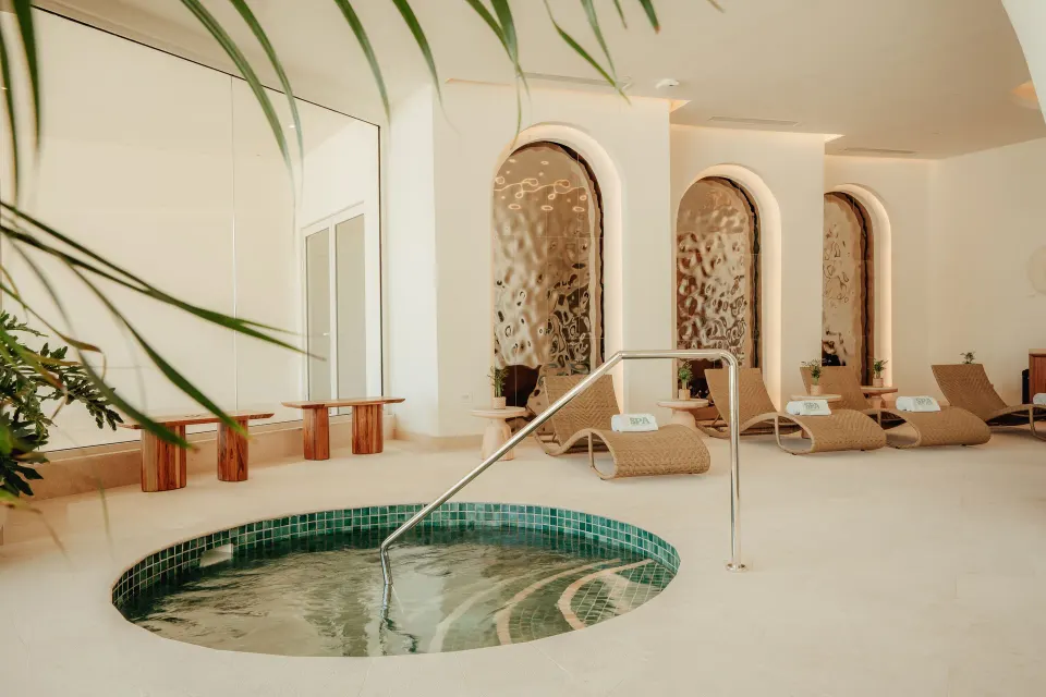 Spa pool with lounge chairs and arched wall niches at JOIA Aruba.