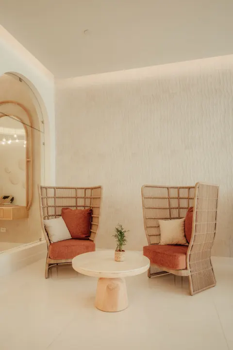 Spa seating nook with two woven chairs, pillows and round table at JOIA Aruba.