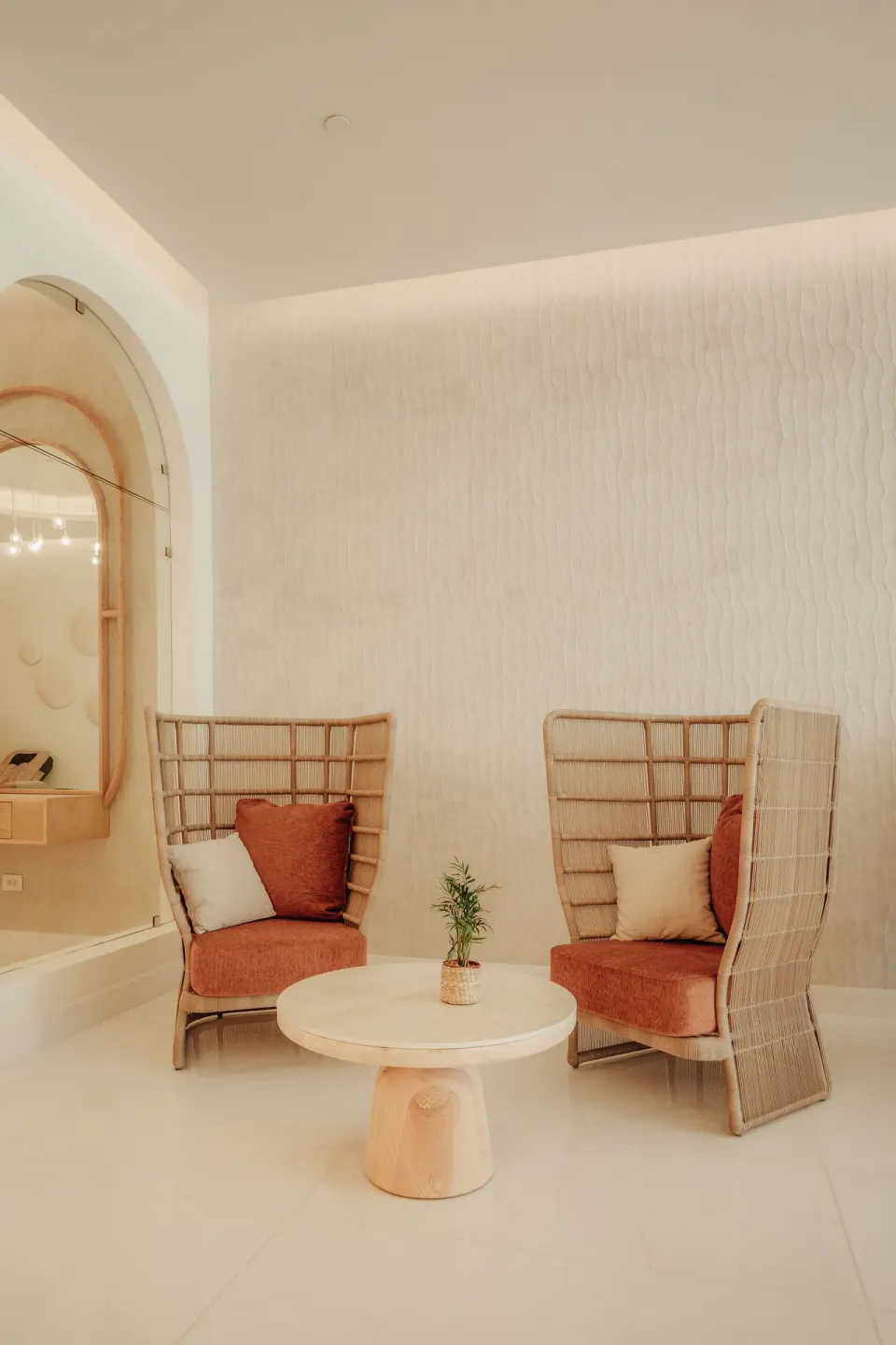 Spa seating nook with two woven chairs, pillows and round table at JOIA Aruba.