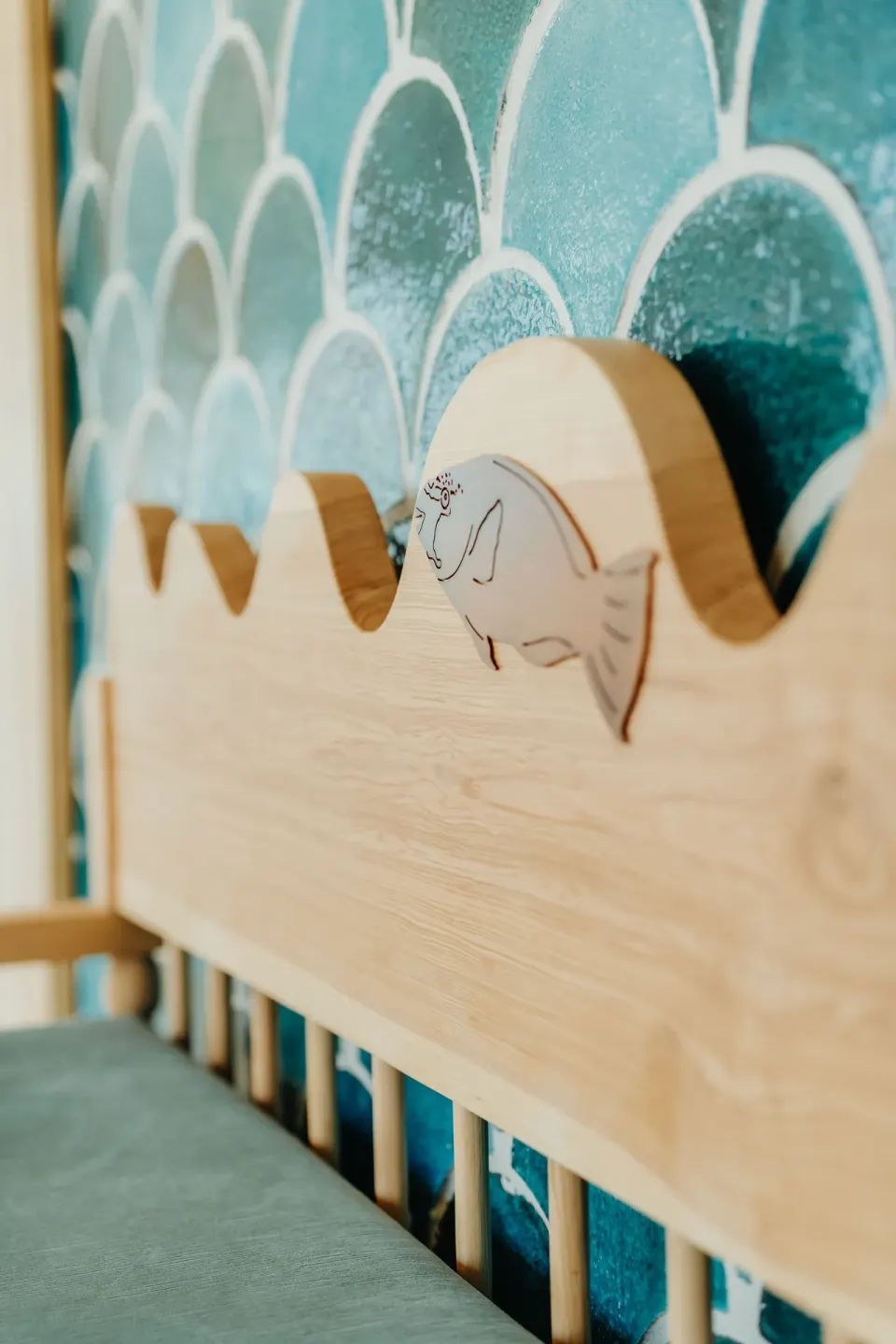 Wood bench detail with manatee motif against blue tile at JOIA Aruba.