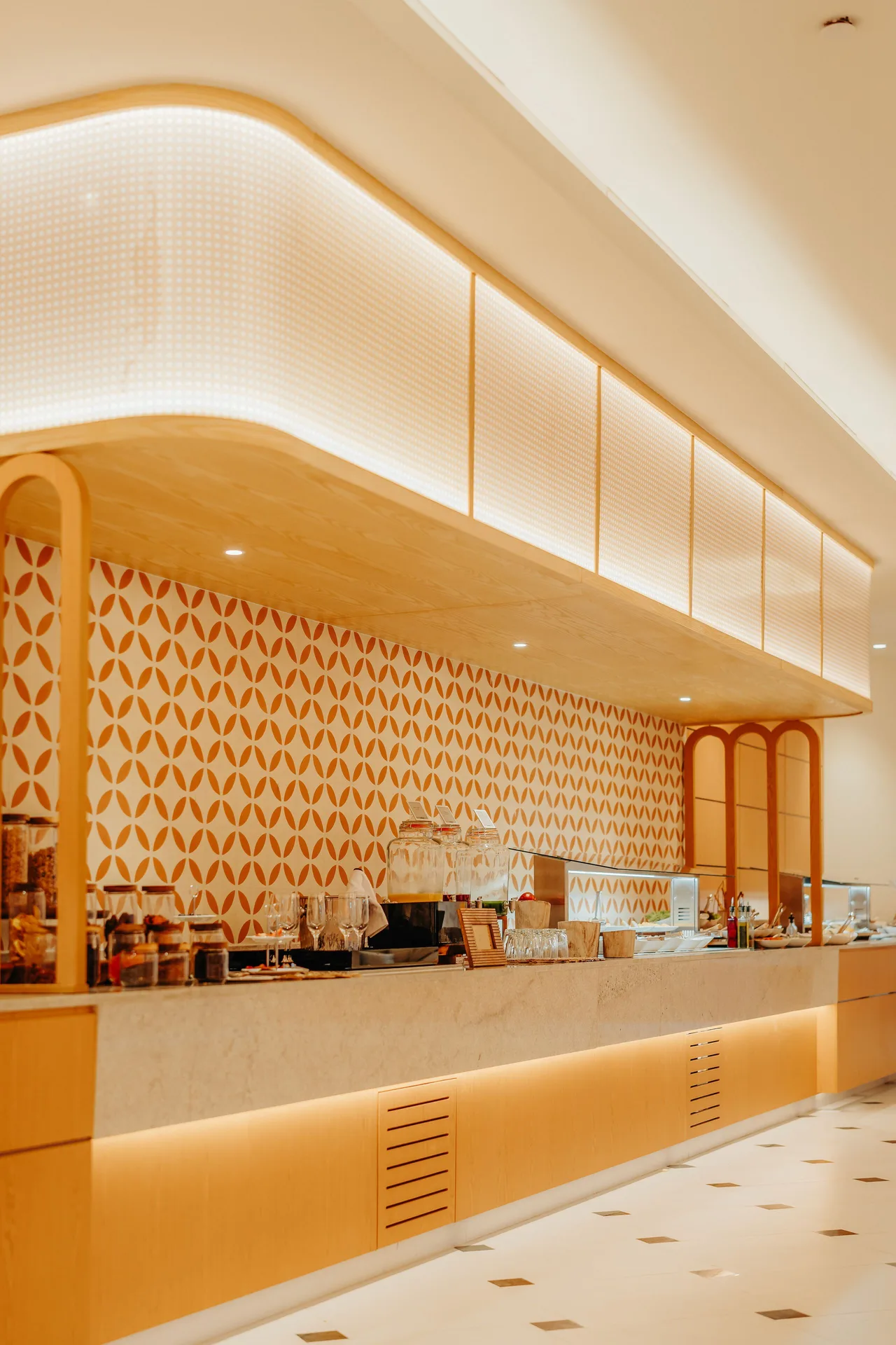 A bright café counter with patterned tile and display cases is shown at JOIA Aruba.