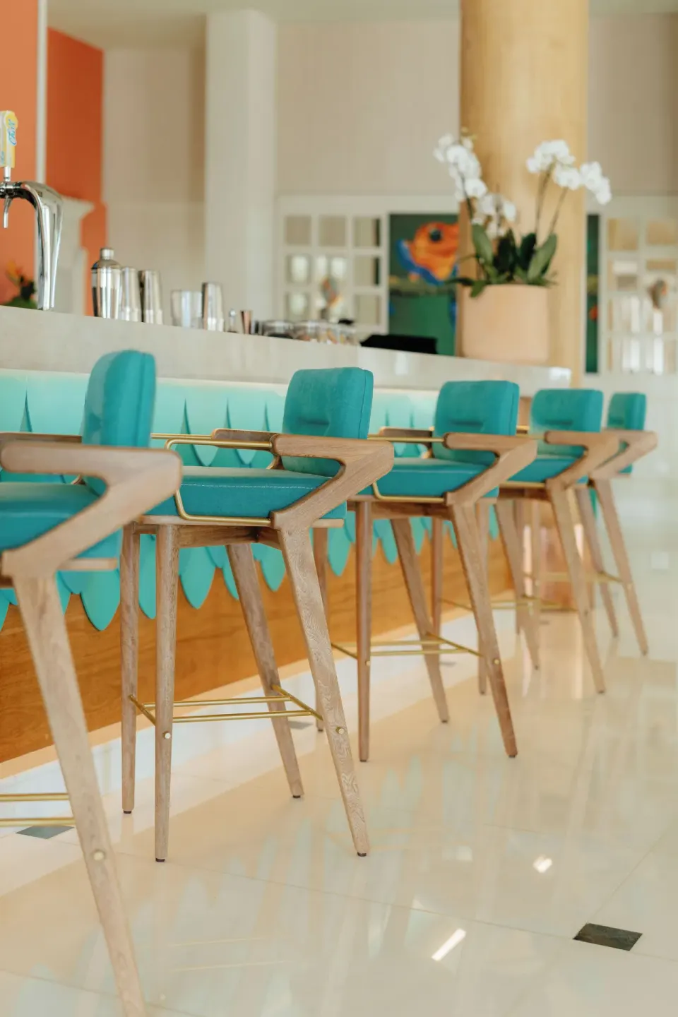 Teal bar stools lined along a bright counter at JOIA Aruba.