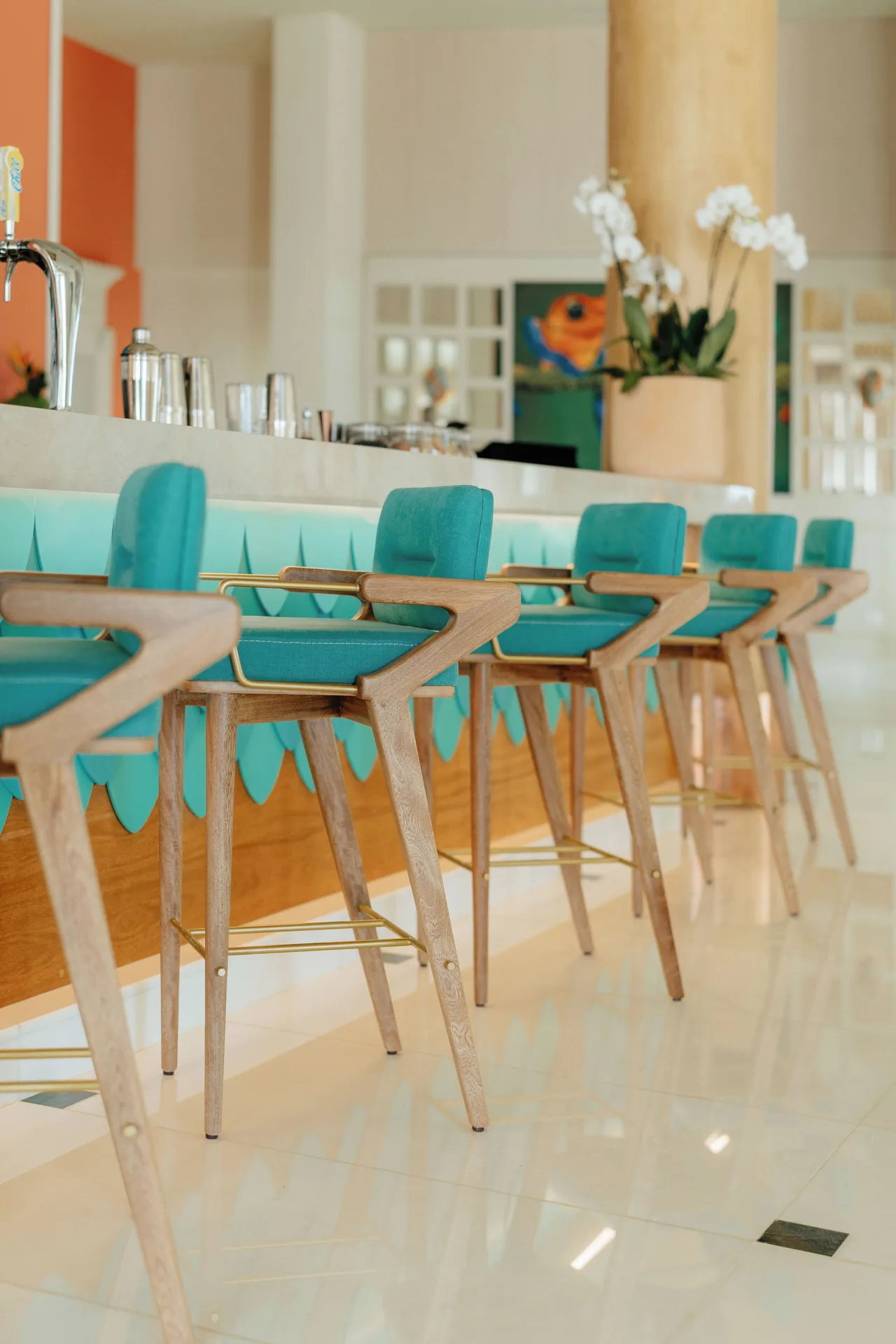 Teal bar stools lined along a bright counter at JOIA Aruba.
