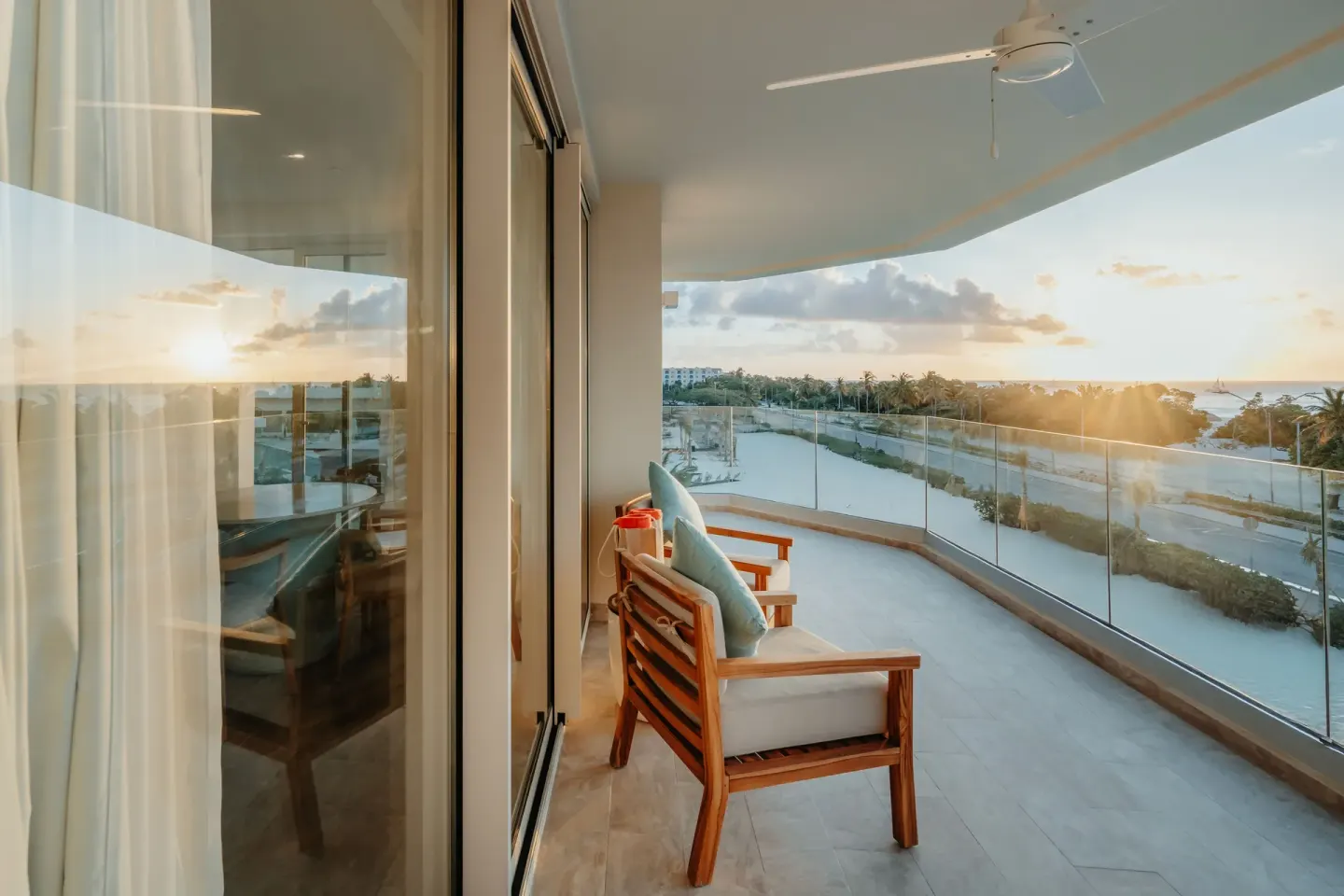 Royal Suite Oceanfront balcony at JOIA Aruba with lounge chair, glass railing, and sunset ocean view.