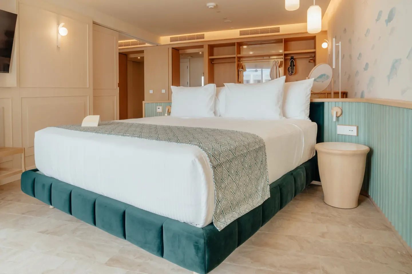 Oceanfront suite bedroom with king bed and open wardrobe at JOIA Aruba.