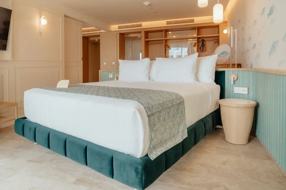 Oceanfront suite bedroom with king bed and open wardrobe at JOIA Aruba.
