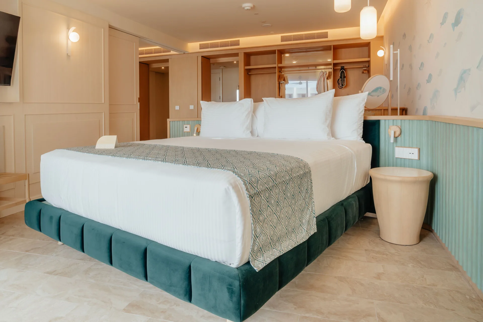 Oceanfront suite bedroom with king bed and open wardrobe at JOIA Aruba.