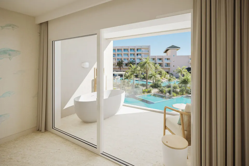 Suite balcony with soaking tub and pool view at JOIA Aruba.