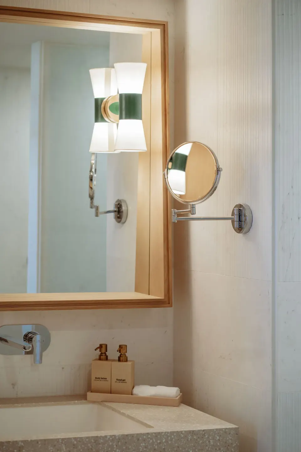 Pool View Suite bathroom vanity with mirror, sconce, and bath amenities at JOIA Aruba.